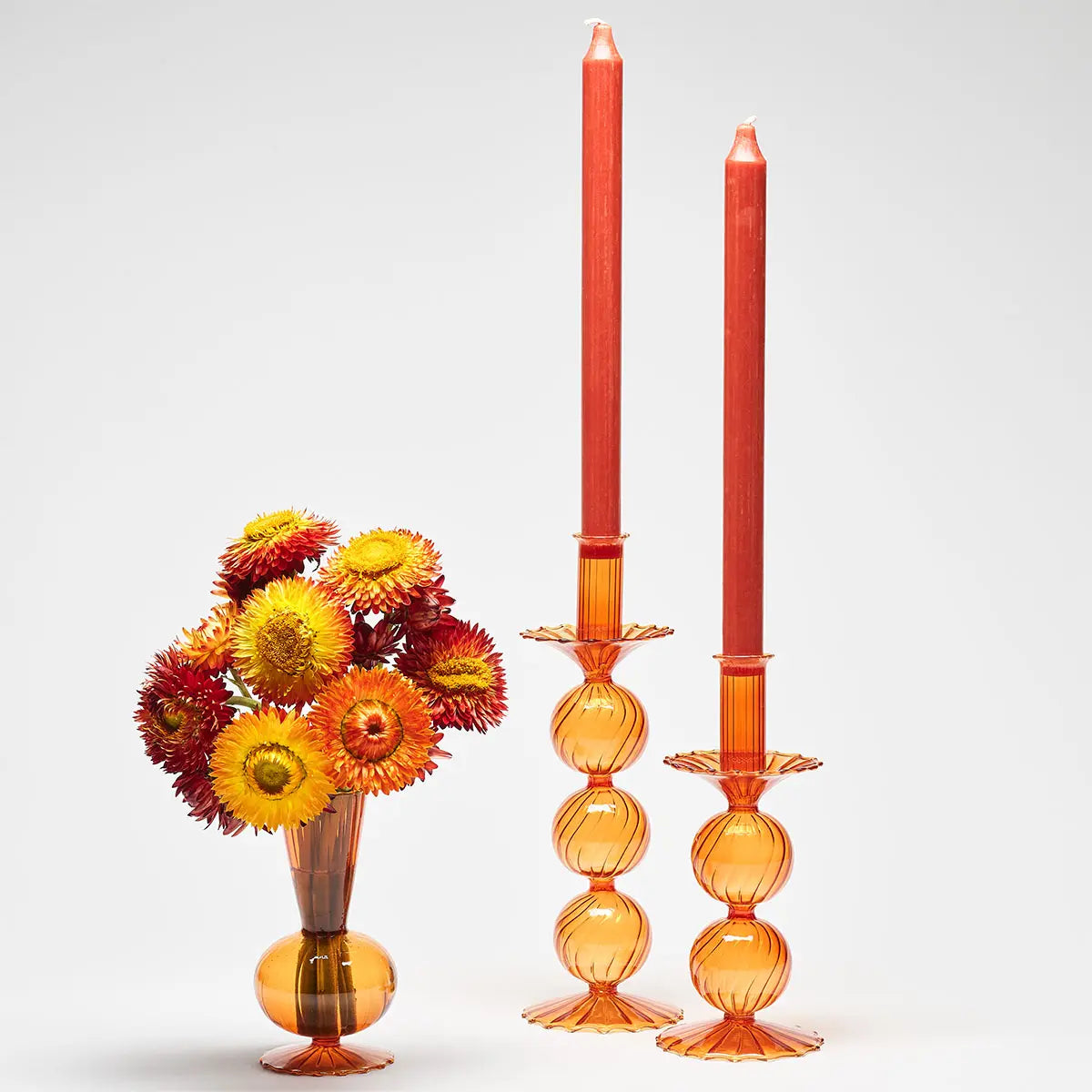 Kim Seybert Bella Amber Candlesticks set on a table with flowers and candles
