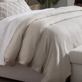 Lili Alessandra Rain Duvet Cover in Natural Cotton and Linen draped on a bed in a room