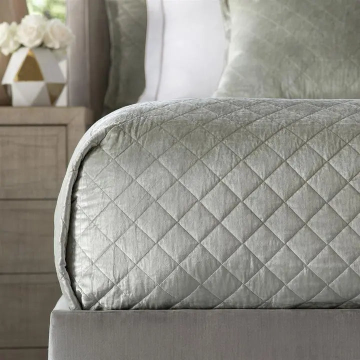 Lili Alessandra Chloe Diamond Quilted Coverlet in Ice Silver Velvet draped on a bed in a room