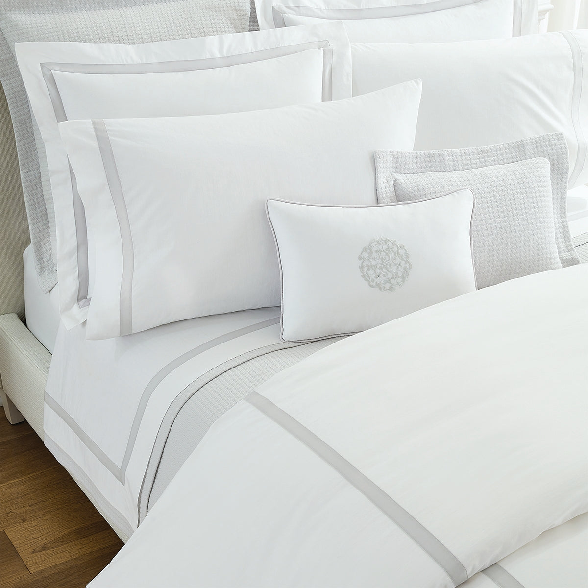 Image of the top left corner of a bed made with the Sferra Estate collection bedding set in white