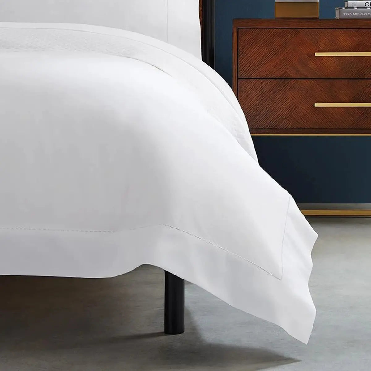 Sferra Celeste White Duvet Cover Draped on top of a bed frame in a room