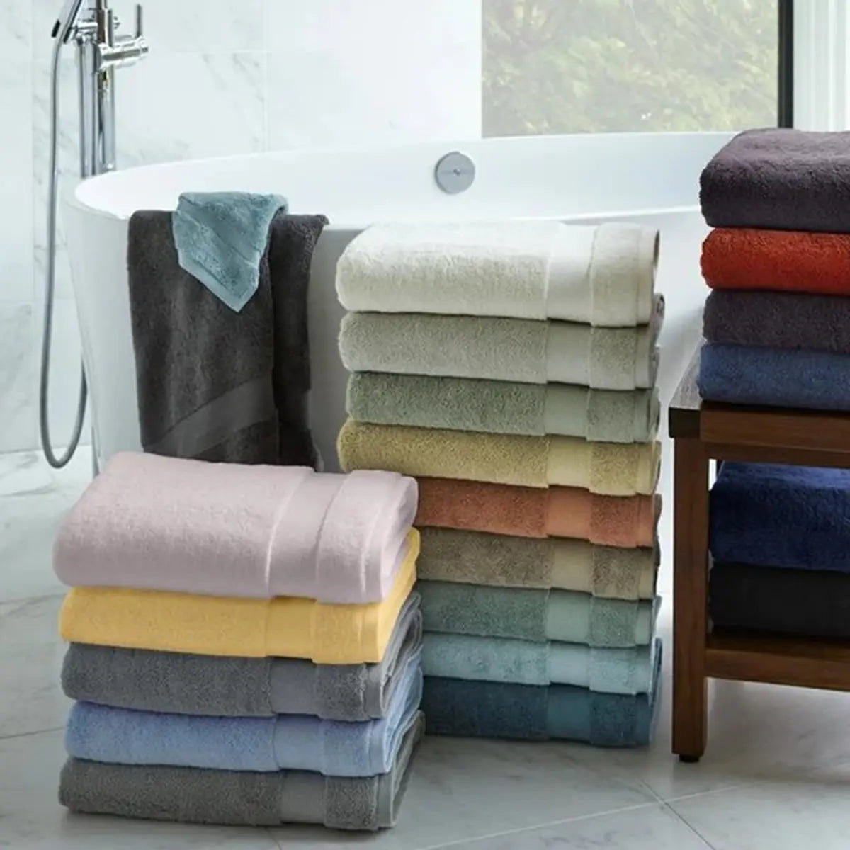 Sferra Bello Bath Towels in various colors stacked together in a bathroom
