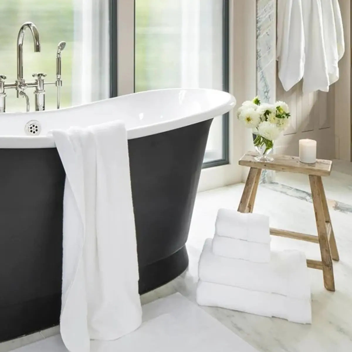 Sferra Bello Towels hung on a bath tub and stacked on the bathroom floor