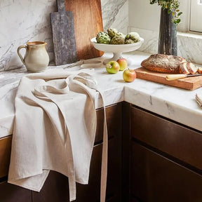 Sferra Cucina Apron in Natural laid on a kitchen counter