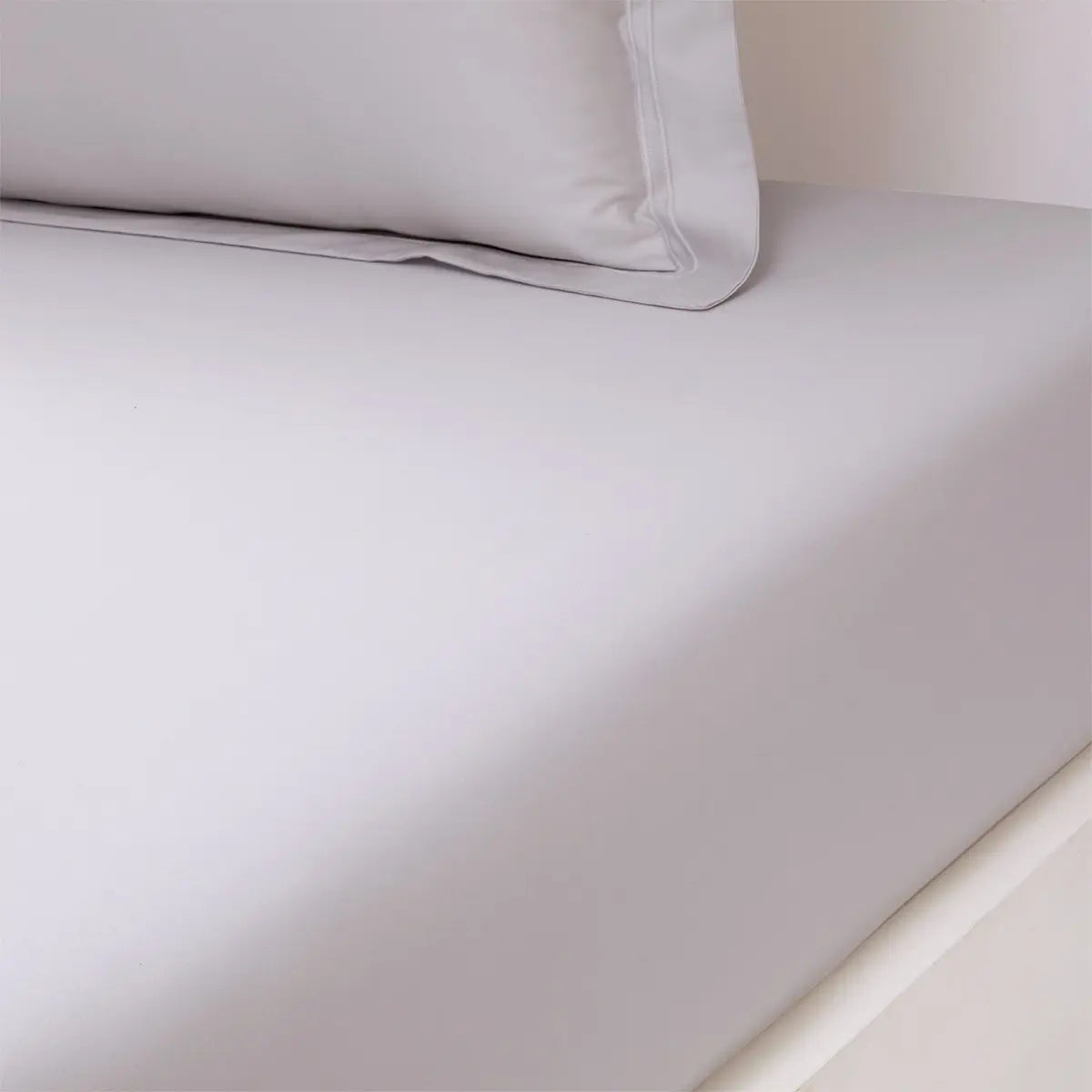Yves Delorme Triomphe Fitted Sheet in Silver on a bed