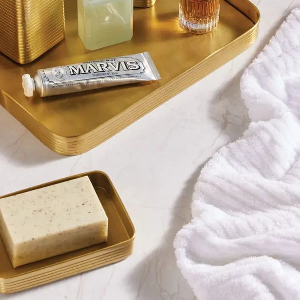 Pigeon and Poodle Adelaide Rectangular Soap Dish in Matte Gold Brass set on the counter next to other items in the collection