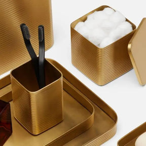 Pigeon & Poodle Matte Gold Brass Adelaide Tray in Set of 2 with a toothbrush holder and canister with cotton balls.