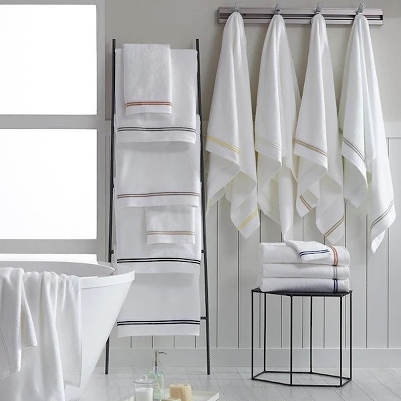 Image of hanging white towels with various color striped from the Sferra bath collection